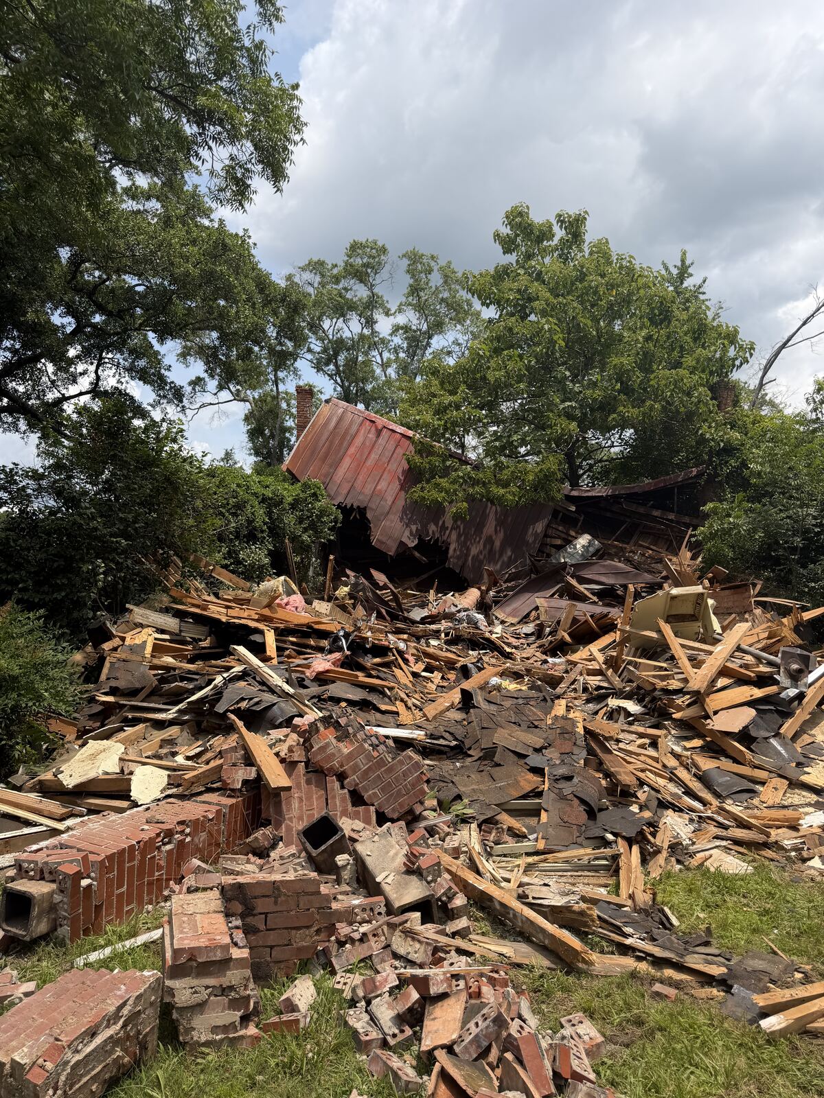 Demolished structure mid-teardown with brick chimney rubble and lumber debris pile